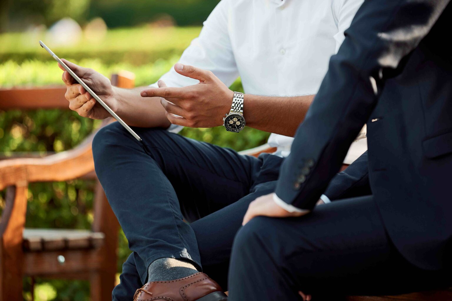 Homme avec une montre qui pointe du doigt l'écran d'une tablette à un autre homme